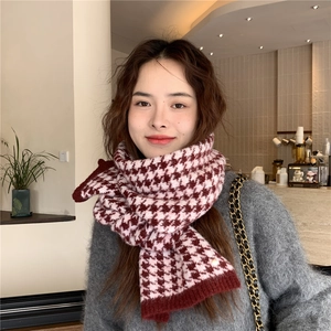 Close-up of red and white houndstooth pattern on thick knitted scarf worn by a model