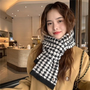 Detail of knitted houndstooth scarf texture paired with stylish wool coat in a cafe