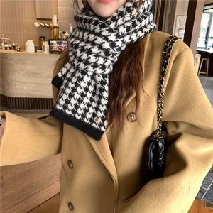 Detail of houndstooth knit scarf with gold charm on camel wool coat for winter fashion
