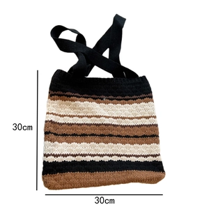 Macro detail of a 30x30cm striped knit tote bag with thick woven texture and black handles