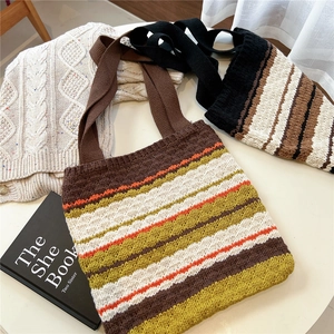 Detail of colorful striped knit tote bags in retro style on a minimalist white table