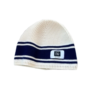 Striped knitted beanie hat in cream and navy blue with a ribbed texture and white logo tag