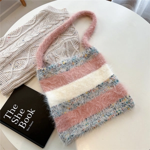 Détails de texture du sac bandoulière en tricot rayé rose et gris sur un bureau épuré