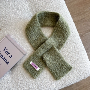Details der Textur des kreuzgestrickten grasgrünen Wollschals mit gewebtem Etikett