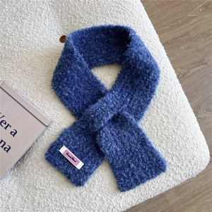 Nahaufnahme eines plüschigen blauen Strickschals mit weicher Textur auf weißem Sofa