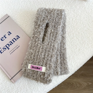 Detailaufnahme der grauen Strickschal-Textur mit Jennie Wool Etikett auf weißem Stoff