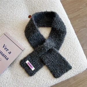 Detail des dunkelgrauen Strickschals mit Wolltextur und lila Markenetikett