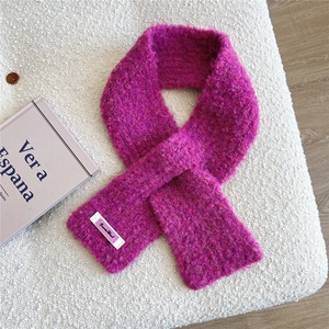 Nahaufnahme der rosa Strickschal-Textur mit weißem Webetikett auf weichem Stoff