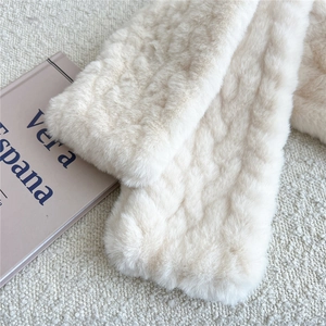 Detail of plush cream-white faux fur scarf with wave texture and soft winter feel