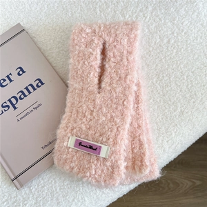 Detail eines rosa Fleece-Halswärmers mit gekreuztem Design und gewebtem Markenetikett