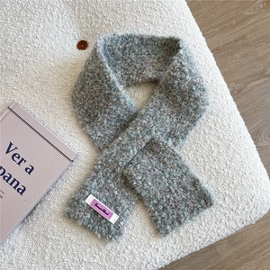 Detail eines mehrfarbigen Wollschal mit Jennis Wool Etikett auf weichem Hintergrund