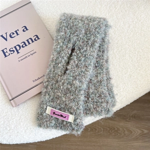 Detailaufnahme des grauen Strickschals mit Woll-Label auf flauschigem weißem Fell