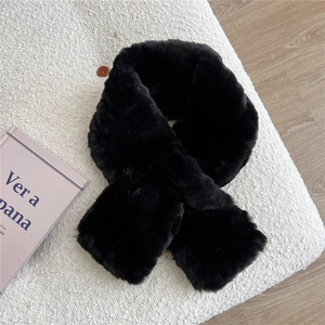 Close-up of soft black faux fur scarf on a white textured cushion with a rustic book decor