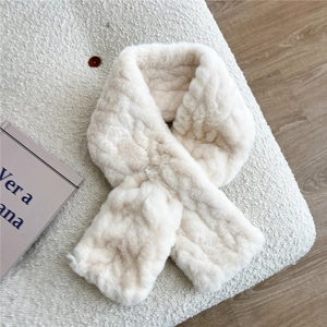 Close-up of cream faux rabbit fur scarf with cross-loop texture on knit background