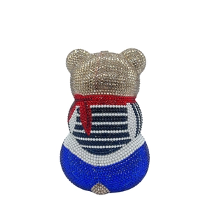 Détails d'un sac de soirée en forme d'ours avec des cristaux colorés et nœud rouge