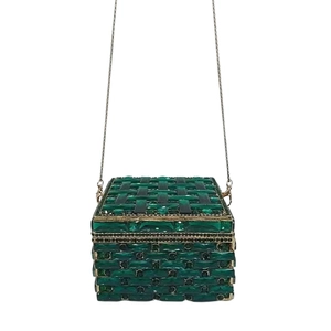 Macro view of emerald green crystal clutch featuring woven gemstone texture and gold chain