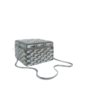 Macro view of crystal square clutch featuring silver metal frame and chain shoulder strap