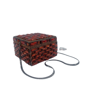 Close-up of rectangular evening clutch with deep amber gemstones and snake chain strap