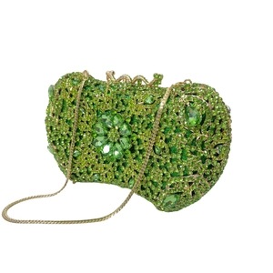 Macro detail of luxury green rhinestone clutch with floral crystal centerpiece and gold chain