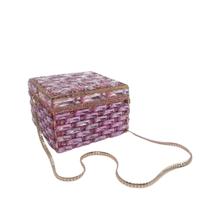 Macro detail of pink crystal rectangle clutch with gold metal frame and snake chain