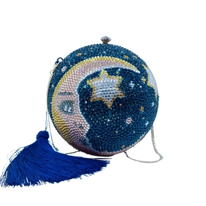 Detail of moon and star rhinestone patterns on a round navy blue evening clutch bag