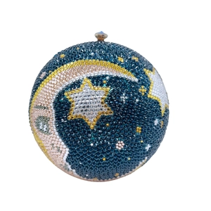 Close-up of spherical evening clutch featuring moon and star rhinestone starfield pattern