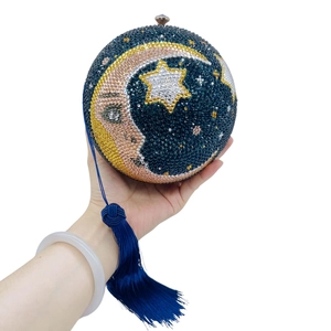 Close-up of spherical rhinestone clutch with moon star pattern and silk tassel detail