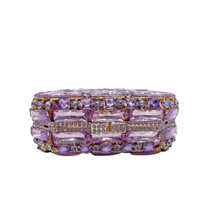 Détail macro d'une pochette de luxe sertie de cristaux violets et cadre doré