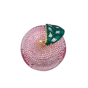 Macro shot of luxury apple-shaped evening clutch bag with pink crystals and leaf detail