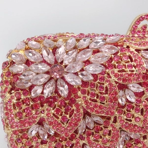 Close-up of pink crystal flowers and heart pattern on golden evening clutch bag