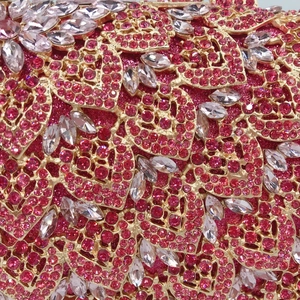 Macro detail of gold hollow-out pattern with pink and white rhinestones on luxury clutch