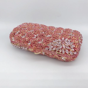 Close-up of pink crystal stone clutch with hollow metal frame and bow clasp