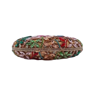 Détail d'une pochette dorée élégante avec motif floral en strass colorés et cadre métal