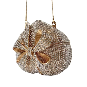 Macro detail of heart-shaped clutch bag with sparkling crystals and golden bow