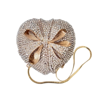 Detail of heart-shaped clutch bag with sparkling crystals and golden bow accent