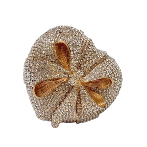 Sparkling heart-shaped clutch bag with crystal pavé and golden metallic bow detail