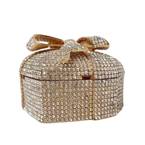 Close-up of heart-shaped gift box clutch featuring full diamond inlay and golden bow detail