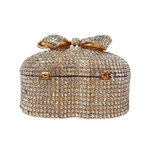 Golden heart-shaped evening clutch bag with sparkling rhinestones and a bow ornament