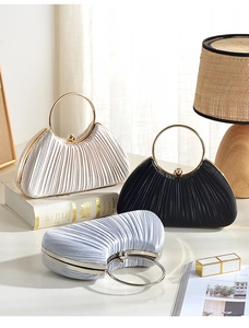 Dettaglio di pochette da sera in raso plissettato con manici dorati in tre colori eleganti