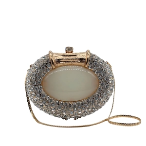 Close-up of luxury oval rhinestone clutch with large faux gemstone and gold chain strap