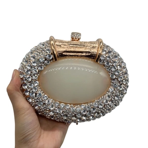 Close-up of oval cat eye evening clutch with rose gold metal frame and white rhinestones