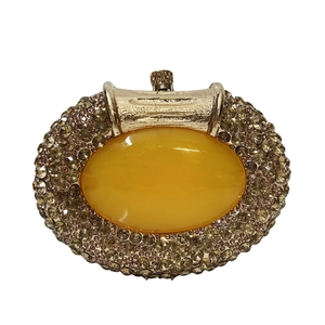 Macro shot of oval amber gemstone surrounded by luxury champagne rhinestones on a clutch