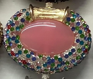 Close-up of luxury oval rhinestone evening clutch with pink cat-eye stone and colored gems