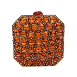 Detailed view of square gold clutch bag with amber crystal rhinestones and round clasp