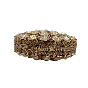 Macro shot of luxury gold evening clutch showing intricate hollow patterns and crystals