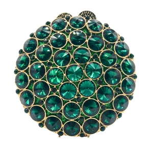 Macro detail of round evening bag with green crystals and gold metal finish