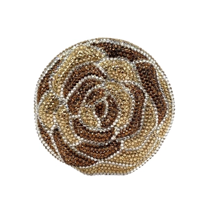 Detailed close-up of a floral evening clutch with golden rhinestones in a rose shape