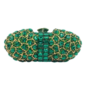 Detailed close-up of emerald green rhinestones set in golden metal luxury clutch bag