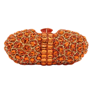 Macro detail of luxury evening clutch featuring orange crystals and fan-shaped metal clasp