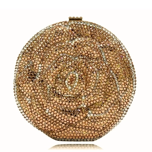 Close-up of a round floral evening clutch bag with dense rhinestones and rose gold metal clasp